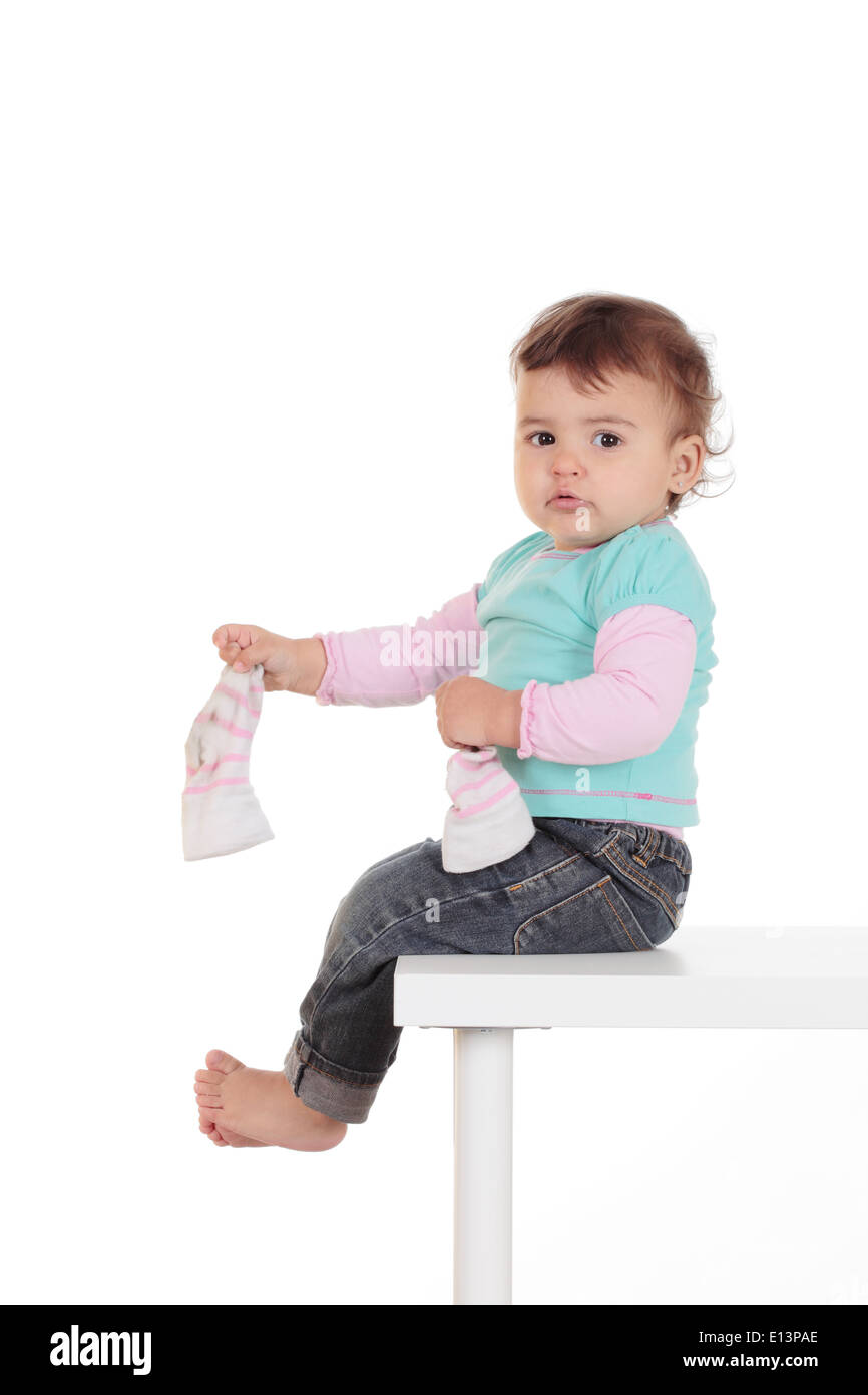 kleines Mädchen auf einem Tisch spielen mit ihren Socken Stockfoto
