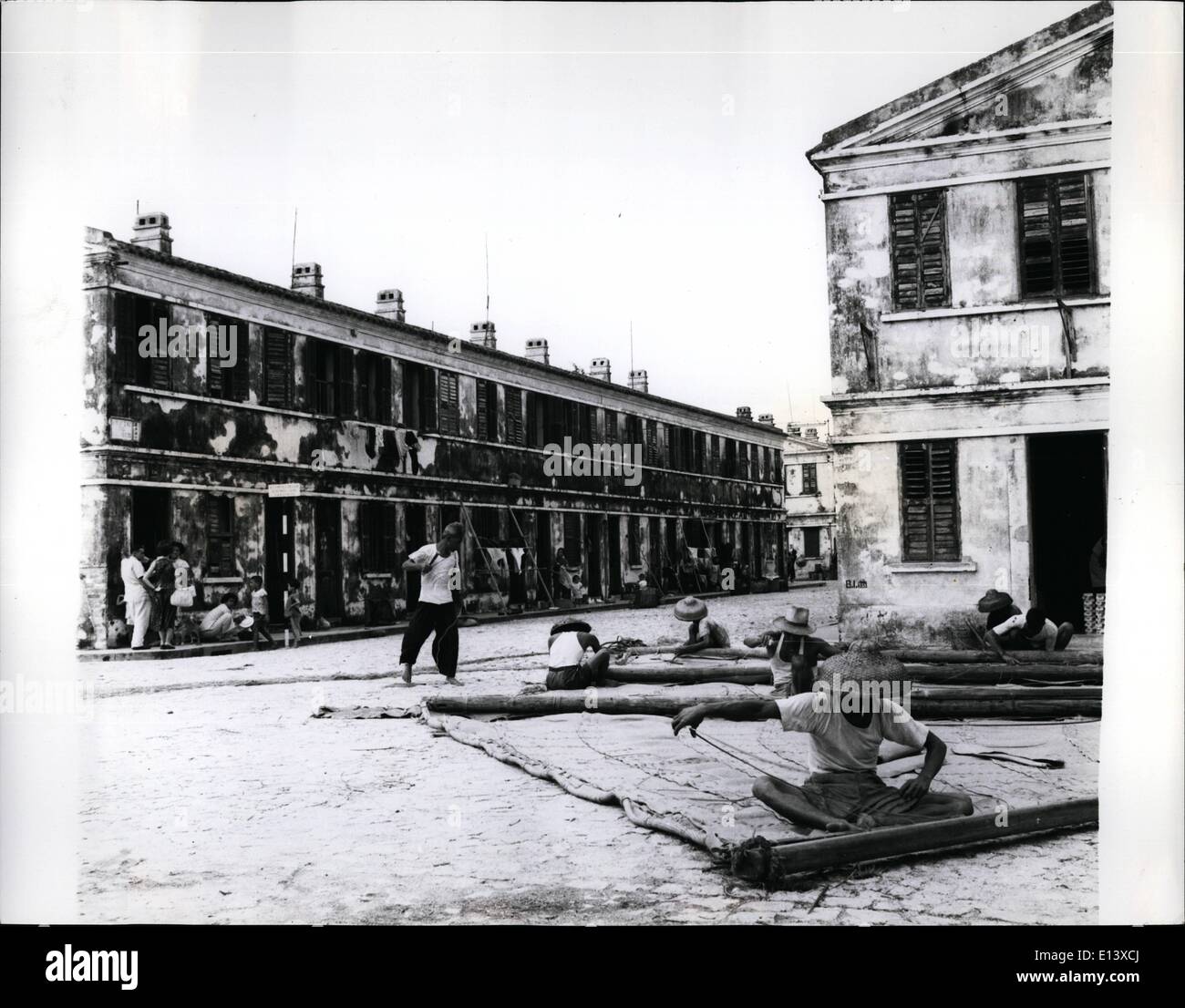 27. März 2012 - eine typische Straßenszene in Macao; Männer sind weben Rush-Matten bei Männern und Frauen Chat außerhalb einer Reihe von zweistöckigen Häusern gesehen; Großteil der Eingeborenen soziale Leben findet auf den Bürgersteigen. Stockfoto