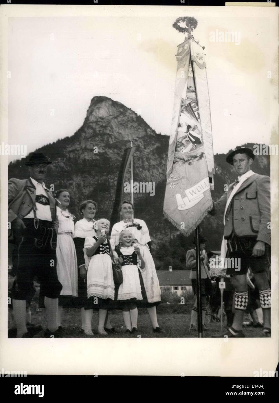 4. April 2012 - hält ein junger Mann aus einem der Bezirke Bezirk Fahne, während er von Frauen und Kindern aus anderen Bezirken Eis genießen bewundert wird. Deutsche Passion Play Village ist Schauplatz des Colourfuf National Kostüm fest: Oberammergau, war das kleine Dorf die schmiegt sich am Fuße der Alpen und ist weltweit bekannt als die Sitzung von den spektakulären Passionsspielen der Szene ein weiteres buntes Spektakel als das Costume National-durch die Gassen des malerischen Dorfes Festival Stockfoto