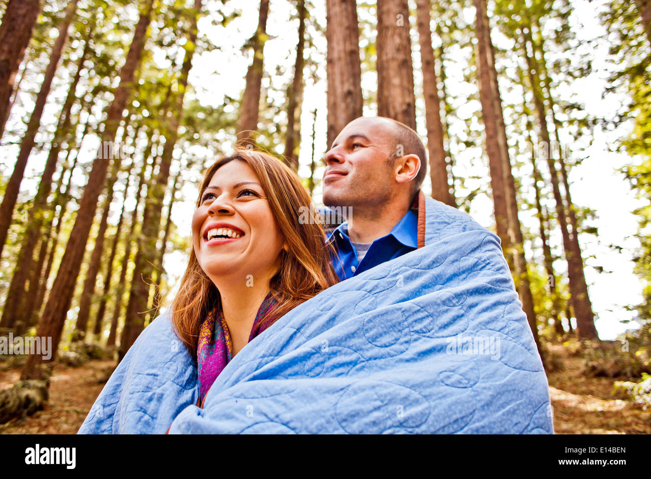 Hispanische paar verpackt in Decke im Wald Stockfoto