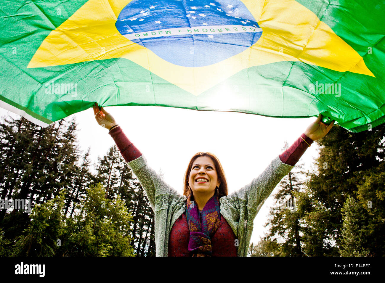 Hispanic Frau fliegende brasilianische Flagge Stockfoto
