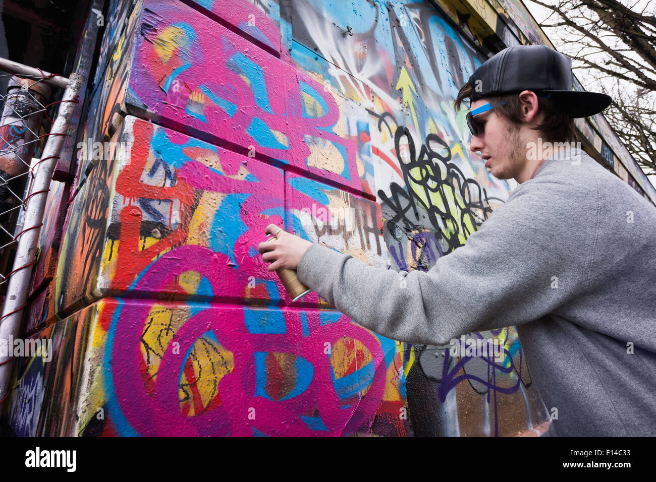 Kaukasische junge Sprühen von Graffiti auf städtischen Wand Stockfoto