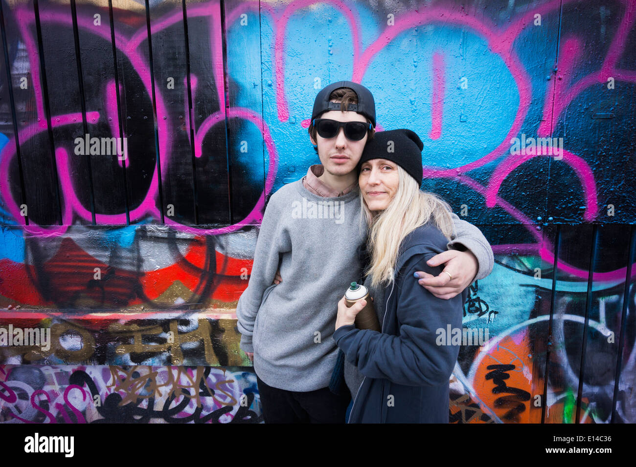 Kaukasische Mutter und Sohn umarmt von Graffitiwand Stockfoto