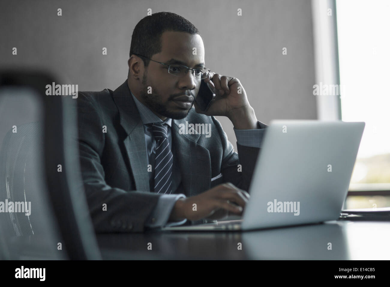 Gemischte Rassen Geschäftsmann reden über Handy am Schreibtisch Stockfoto