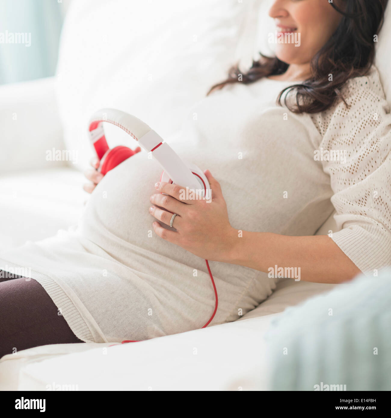 Hispanic schwangeren Bauch Kopfhörer festhalten Stockfoto