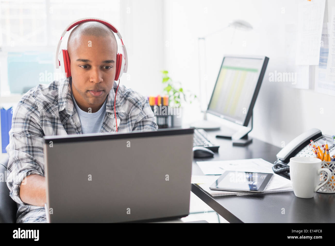 Schwarze Geschäftsmann hören Kopfhörer im Büro Stockfoto