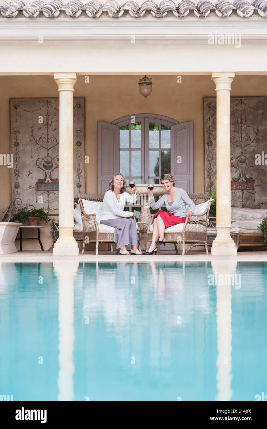 Frauen, die einander Swimmingpool Toasten Stockfoto