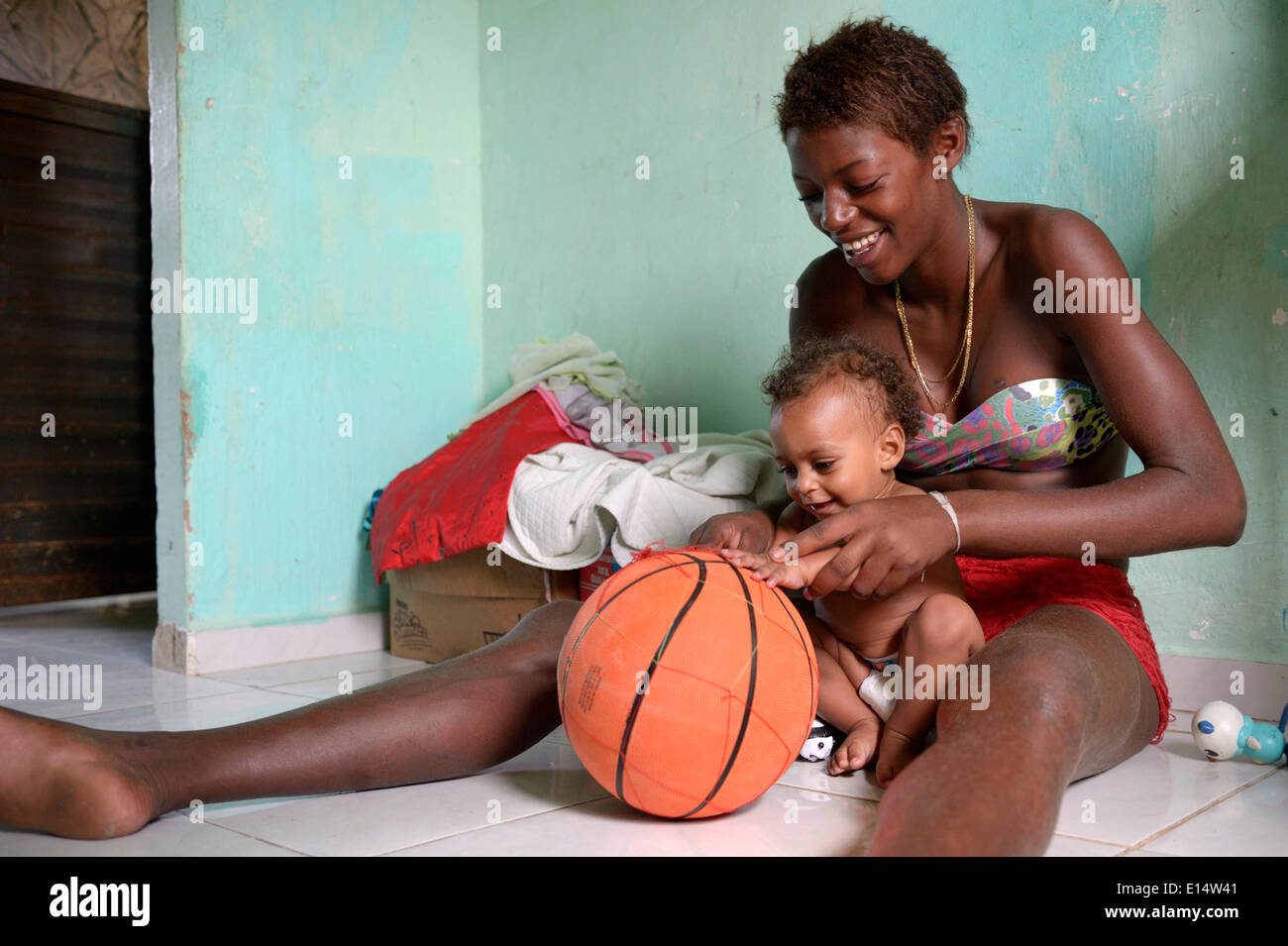 Junge Frau, 15, ehemaligen Straßenkind, das Spiel mit ihrem jüngeren Bruder, 1, mit einem Basketball, Senador Camara Favela Stockfoto