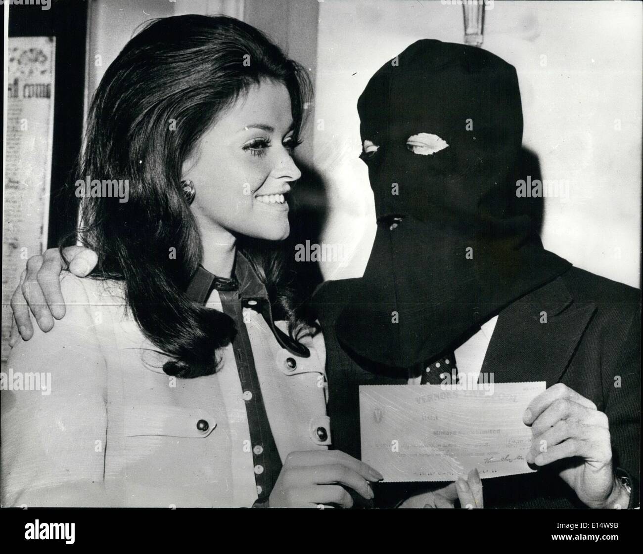 18. April 2012 - vermummte Mann sammelt seine £58,000 Pools gewinnen: A Belfast Büroangestellter trug eine schwarze Kapuze, als er ankam im Waldorf Hotel in London heute einen Scheck für £58.000 von Chase Pool zu sammeln. Warum tragen er die Maske? Er fürchtet die Ira. Seine ist Vater von einem sechs Jahre alten Tochter, und geleitet von einem 15-köpfigen Konsortium die £3 pro Woche gesetzt. Foto zeigt, dass der Hooden Mann bekommt seinen Scheck von Miss Großbritannien Jenny McAdam, im Waldrof Hotel dieser Od terno Stockfoto