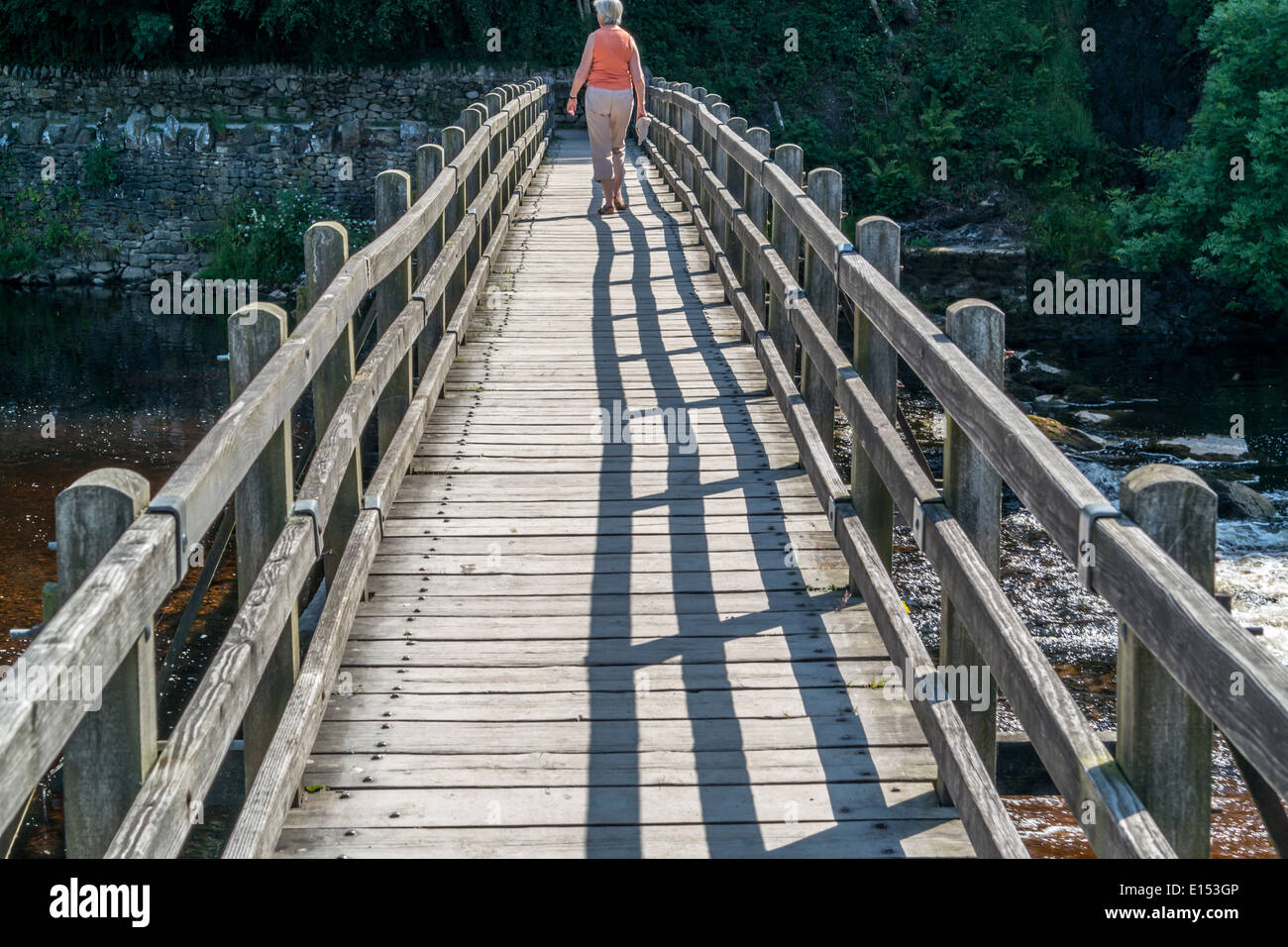 Dame zu Fuß über die Holzbrücke. Stockfoto