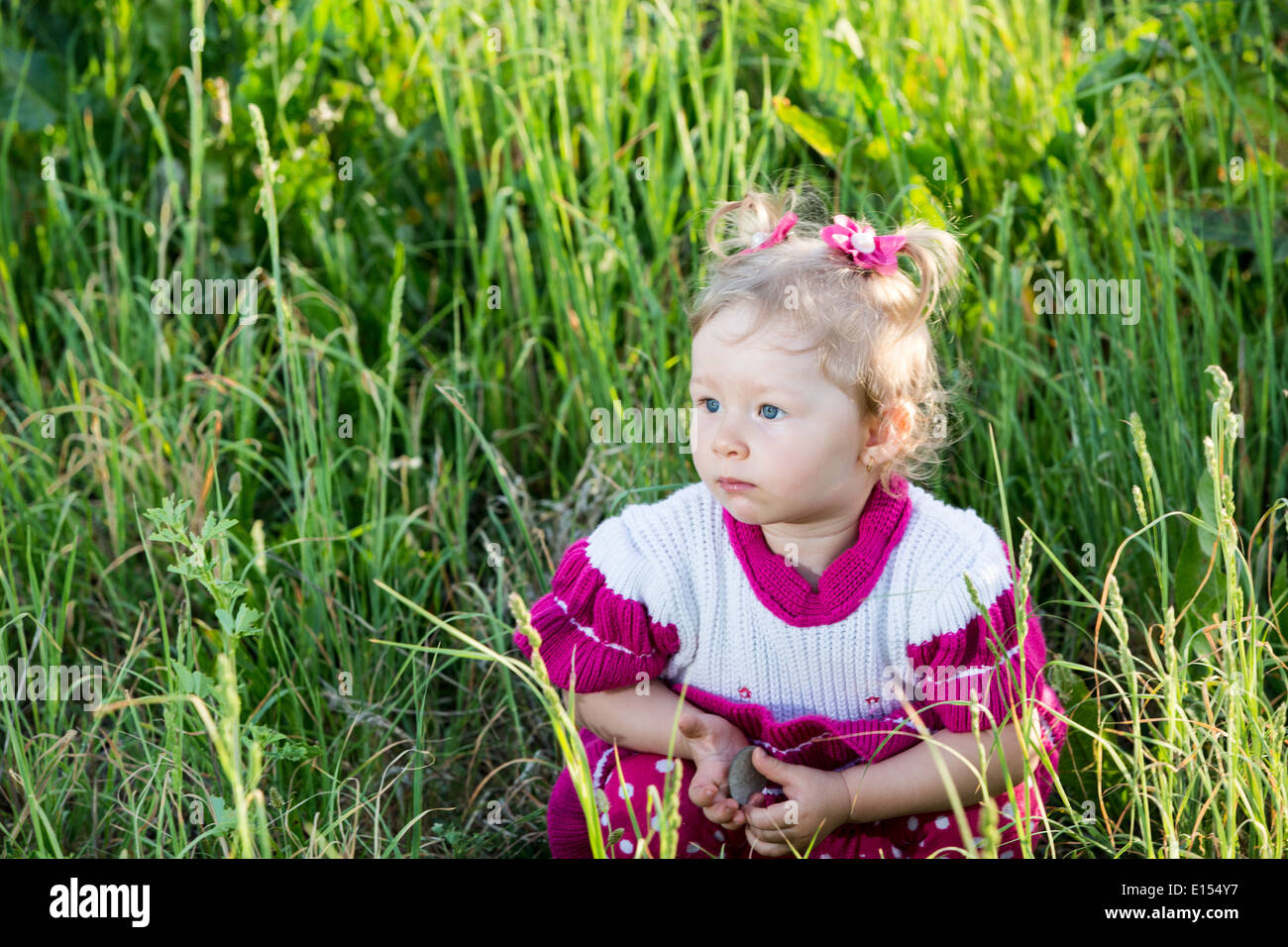 Entzückende kleine Kind Mädchen auf Rasen auf Wiese. Sommer grün Natur Hintergrund Stockfoto