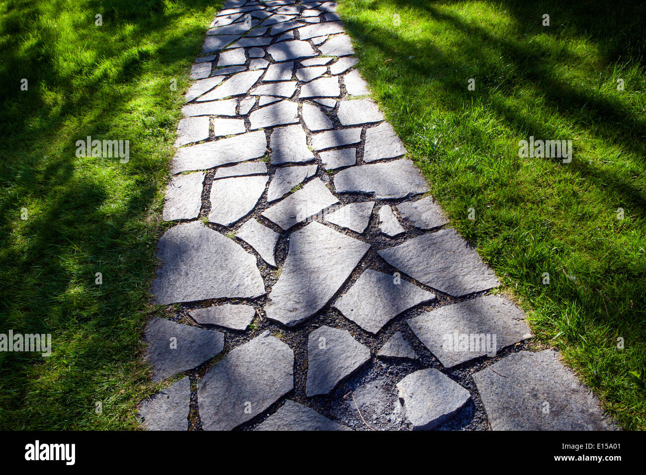 Gepflasterter Gartenweg und Steinweg im grünen Rasen Stockfoto