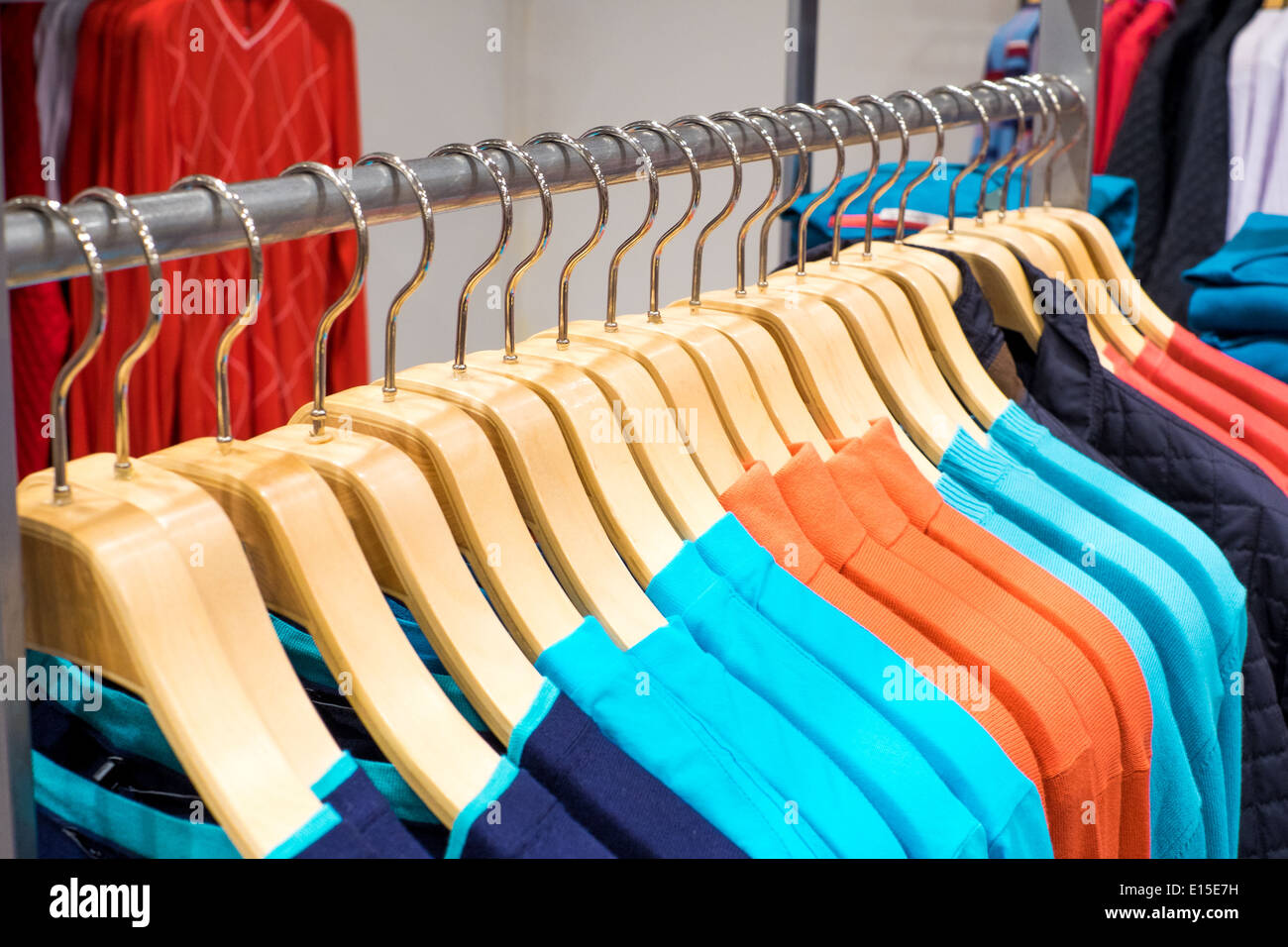 Modische Kleidung auf Bügeln im shop Stockfoto