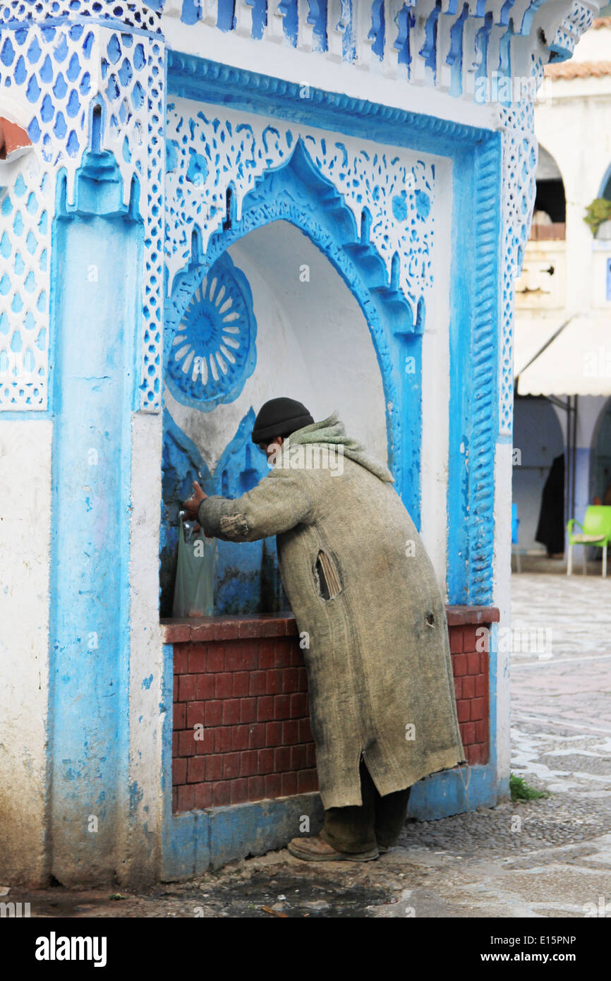 Mann trinkt aus einem Wasserbrunnen in Chefchaouen, Marokko Stockfoto