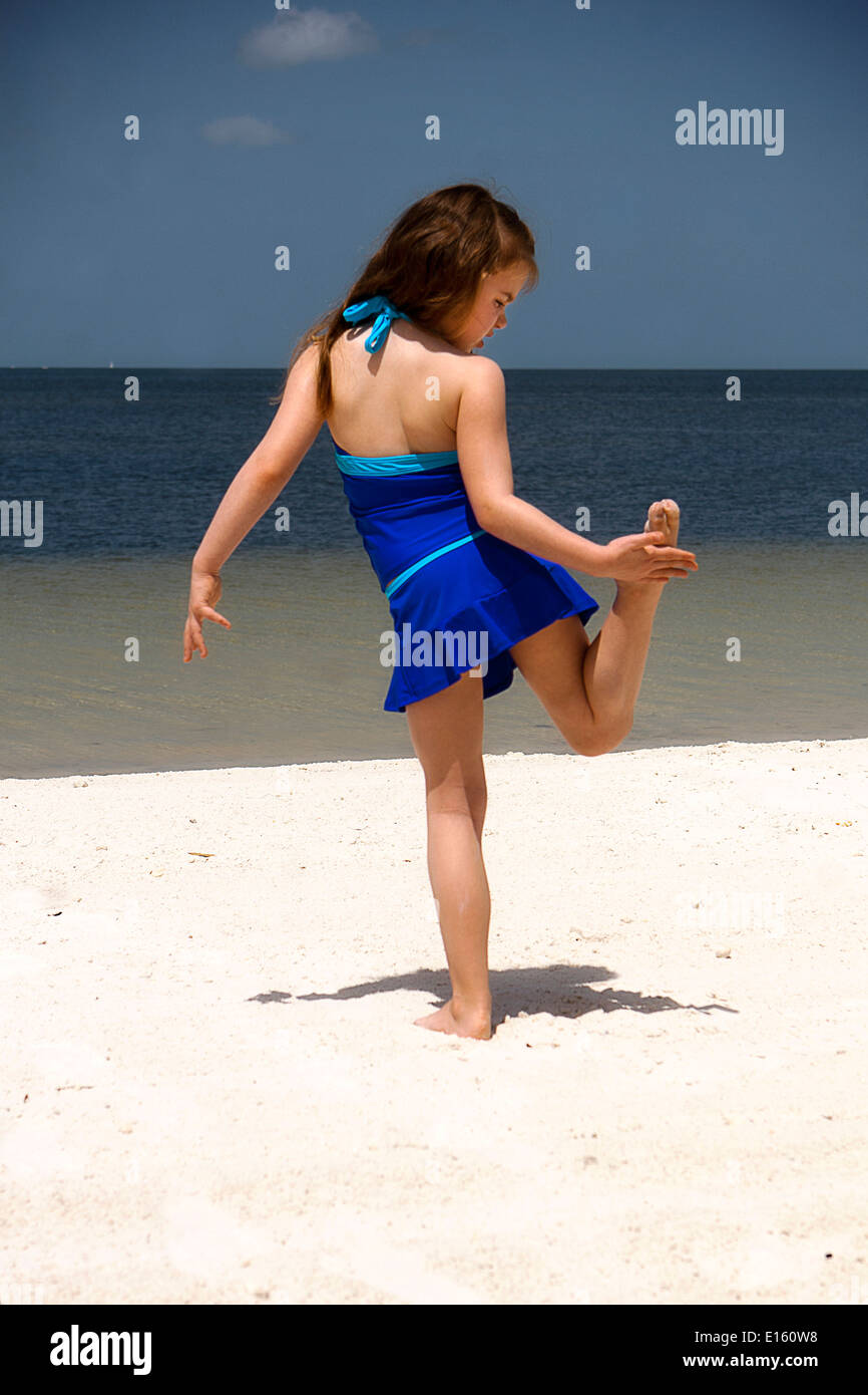 Mädchen stehen auf einem Bein am Strand Stockfoto