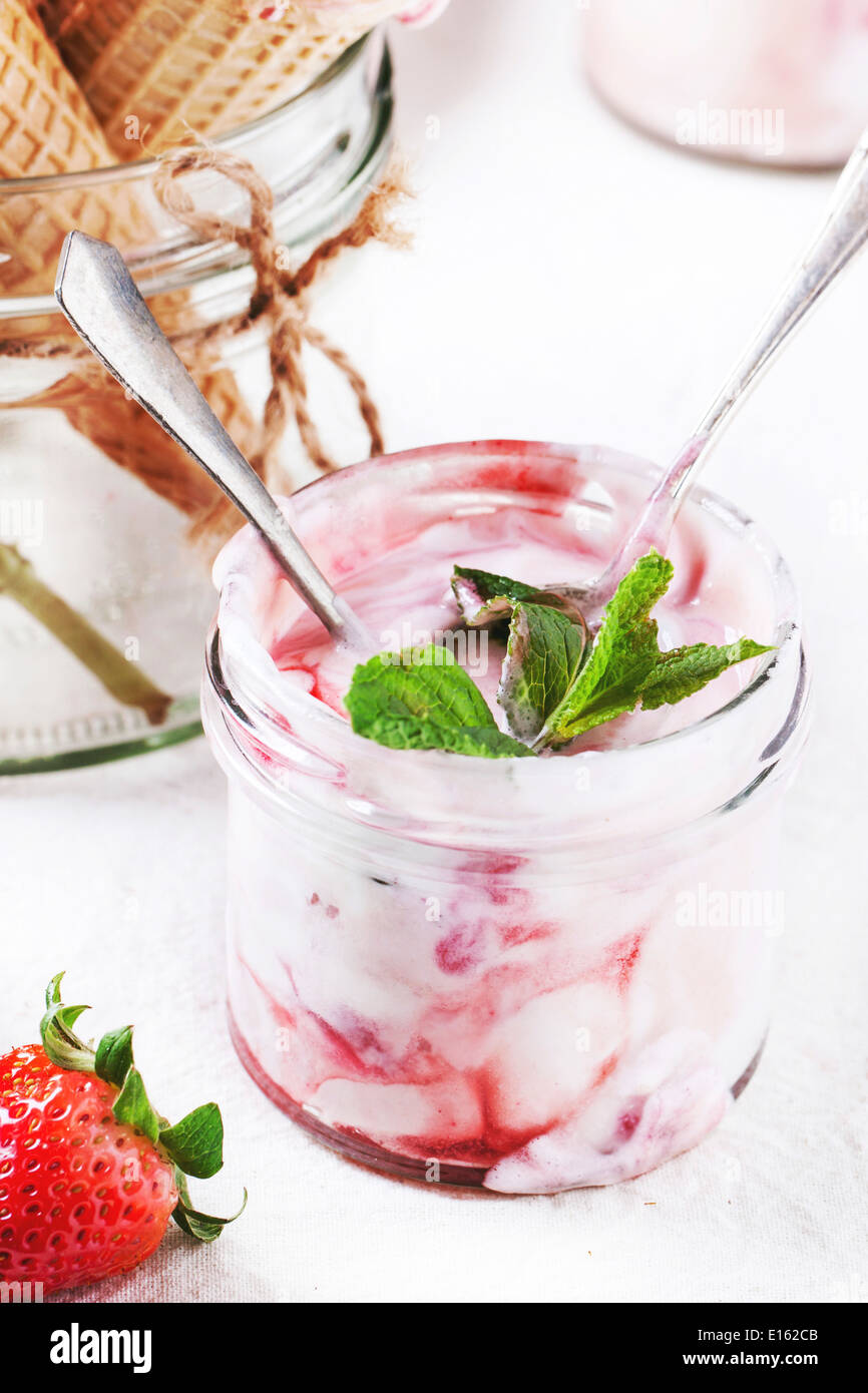 Erdbeereis mit Minze und frischen Erdbeeren serviert im Glas über weiße Textilien. Stockfoto