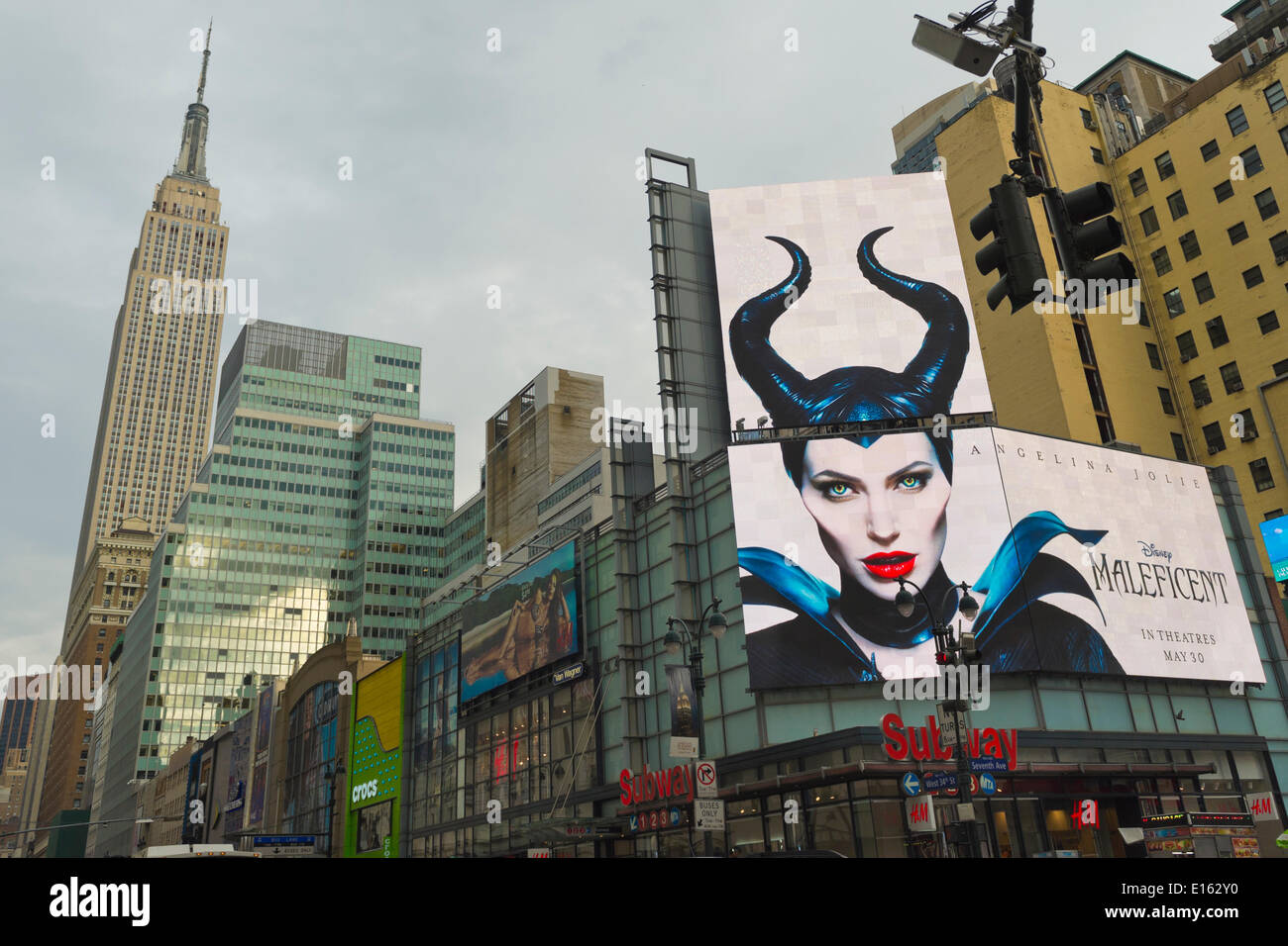 Manhattan, New York, USA - 21. Mai 2014 - A großen Overhead Plakatwand an der 7th Avenue wirbt kommenden Disneyfilm Malefiz, starring Schauspielerin Angelina Jolie mit Empire State Building auf der linken Seite im Hintergrund, während ein angenehmer Frühlingstag in Manhattan. Stockfoto