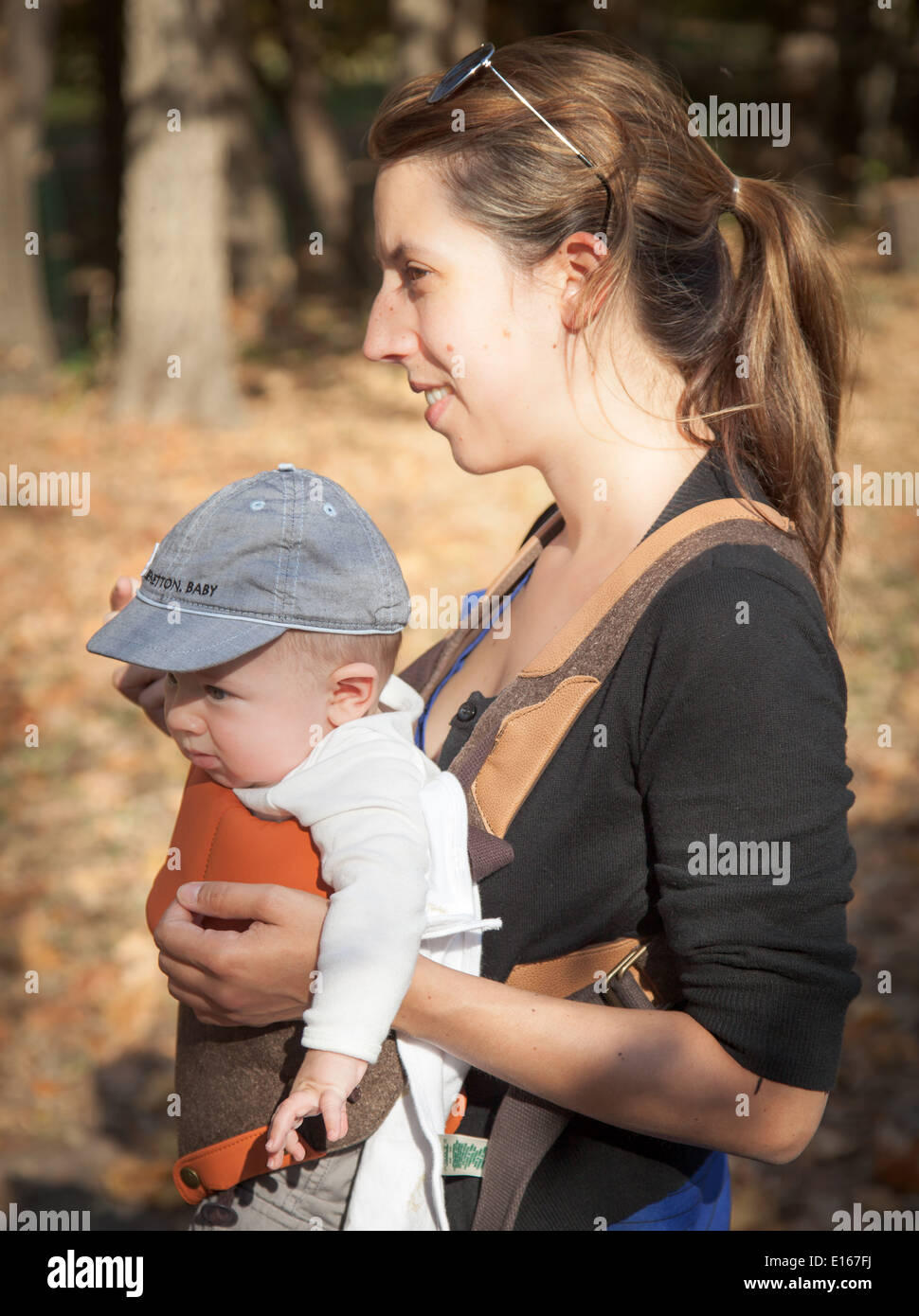 Frau trägt ihr Baby junge in einem Park und lächelnd Stockfoto