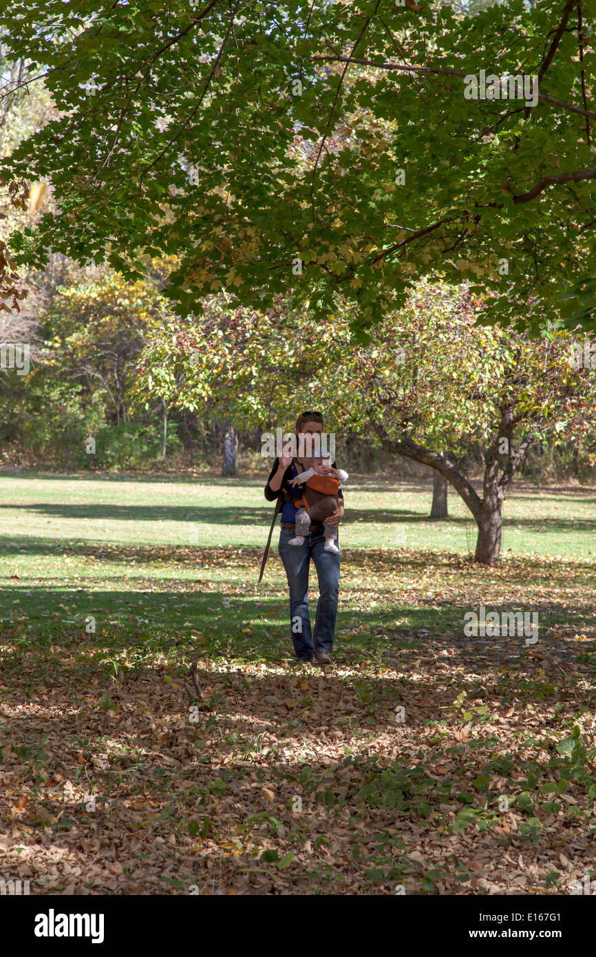 Frau trägt ihr Baby Boy und bewegt sich in einem park Stockfoto
