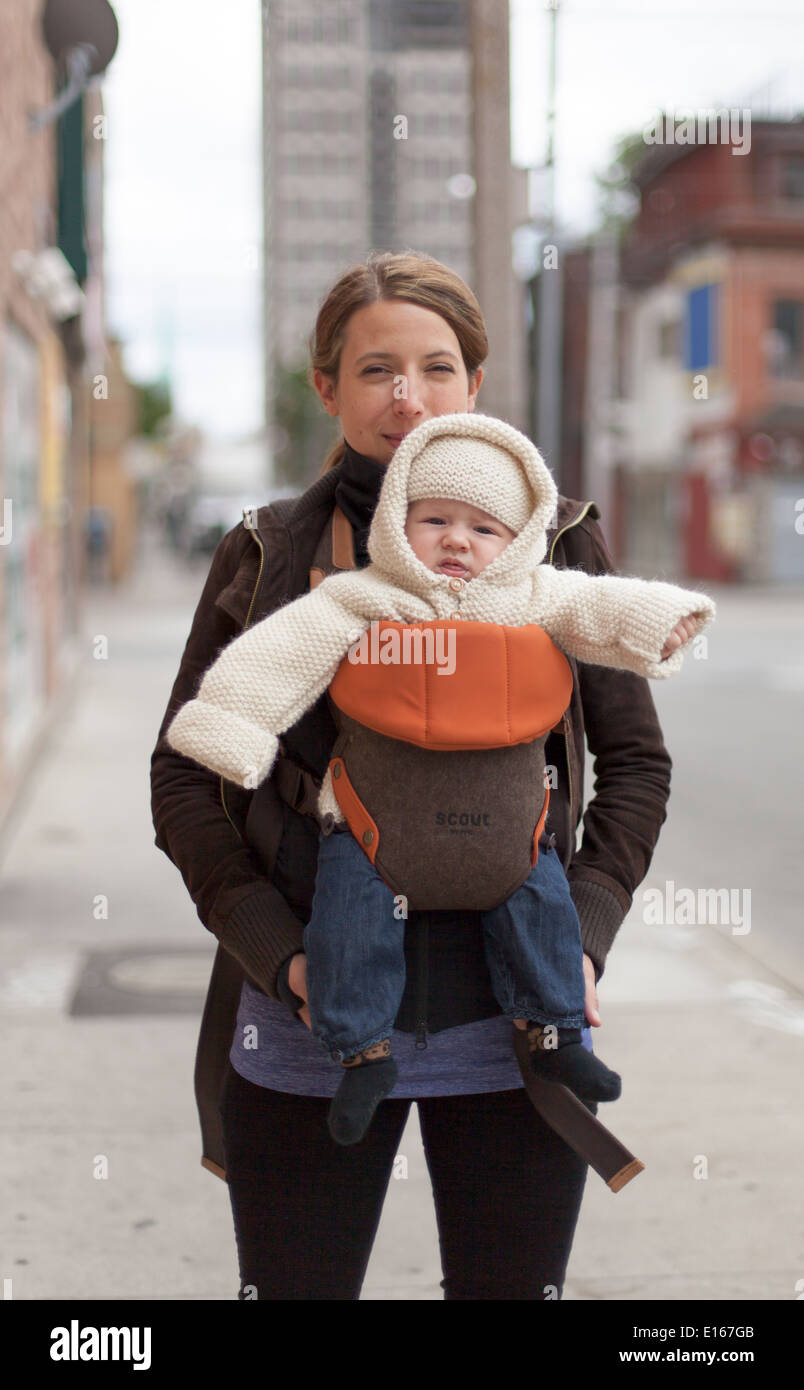 Frau trägt ihr Baby Boy und bewegt sich in einer Stadt Stockfoto