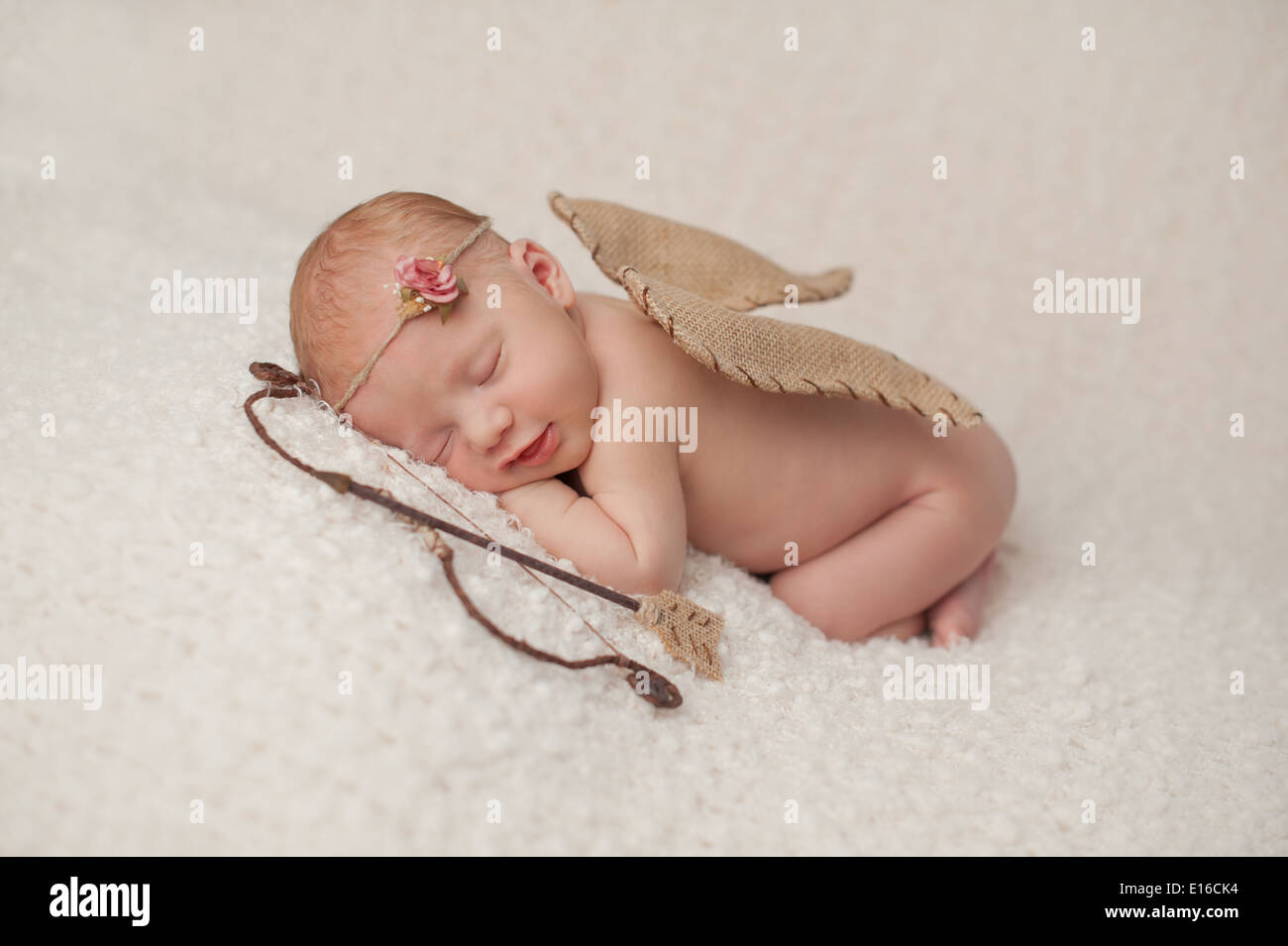 Lächelndes neugeborenes Mädchen in einem Amor Kostüm. Stockfoto