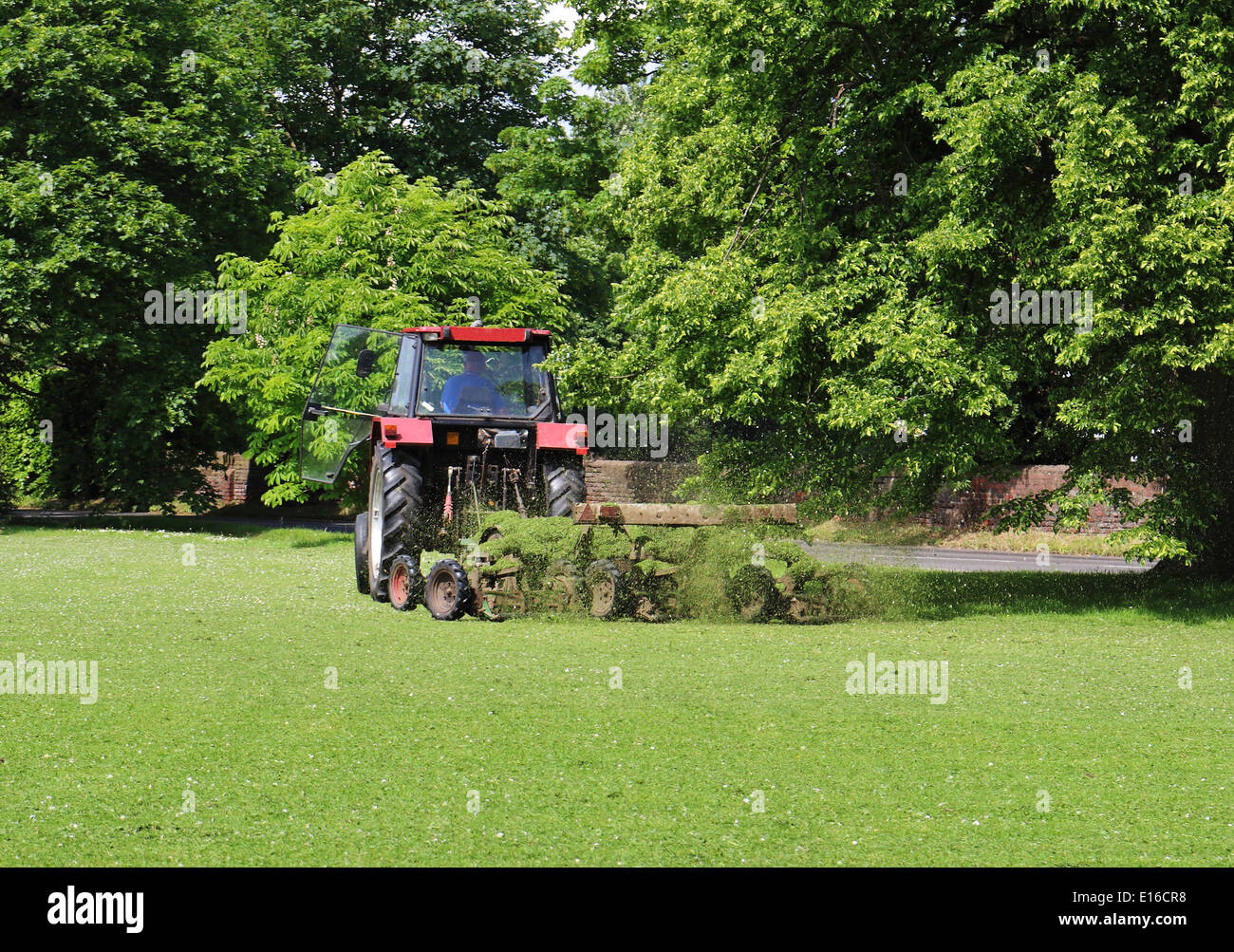 Traktor zieht ein Mähwerk auf einem Dorfplatz Stockfoto