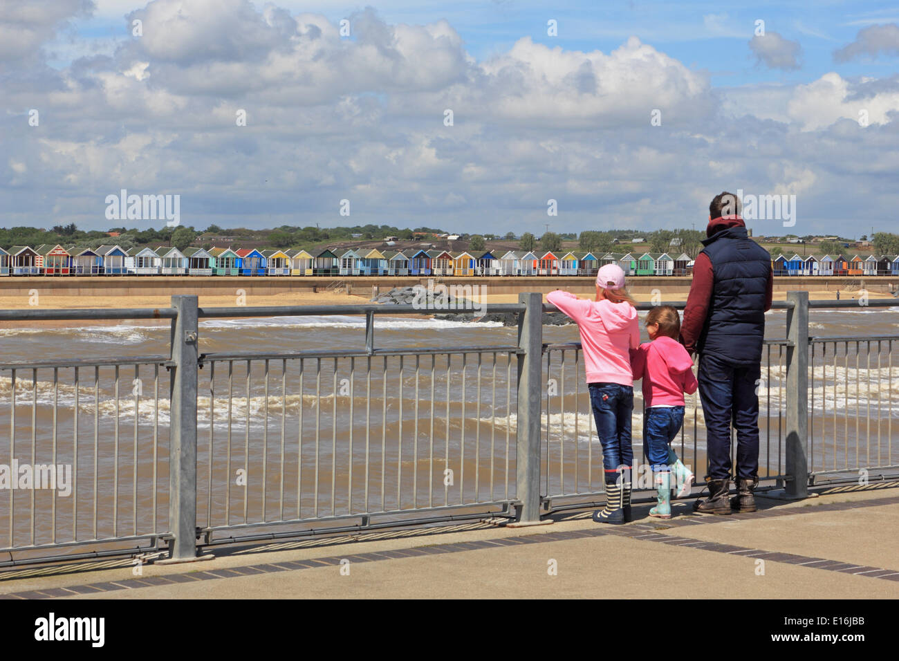 Southwold, Suffolk, England, UK. 24. Mai 2014. Es war ein hellen und luftigen Tag an der Küste von Suffolk zu Jahresbeginn das Wochenende und Feiertagen. Eine Familie genießen den Blick auf das Meer und die farbenfrohe Strandhütten vom Ende des Piers. Stockfoto