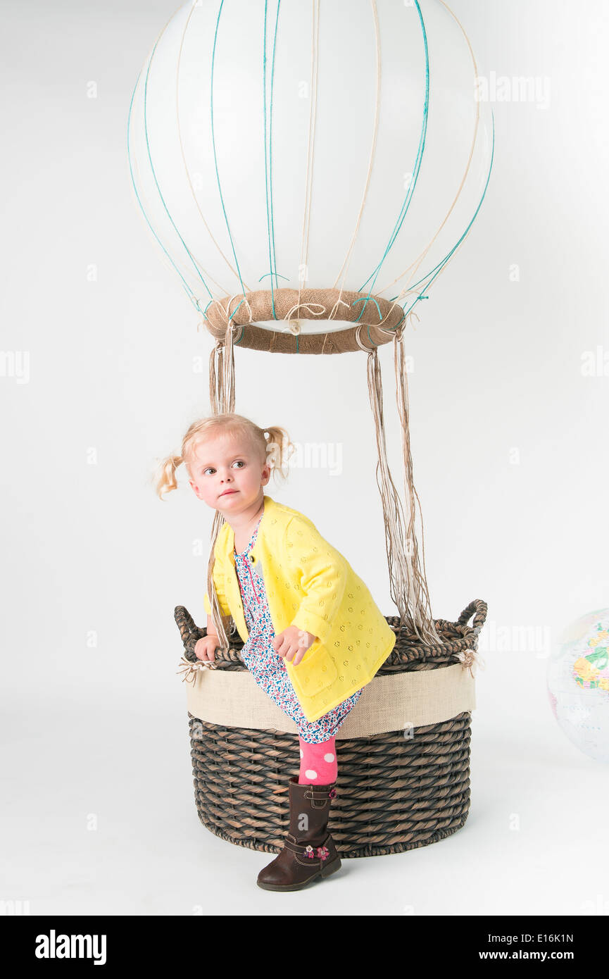 Kleines Mädchen (2-3) klettern aus Heißluftballon Spielzeugkorb Stockfoto