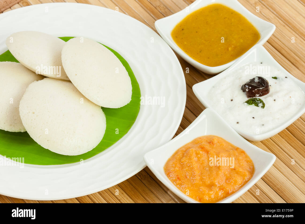 Traditionellen südlichen indischen Frühstück der untätig (Idli) mit Kokos-Chutney, Tomaten Chutney und Sambar auf einem Teller serviert. Stockfoto