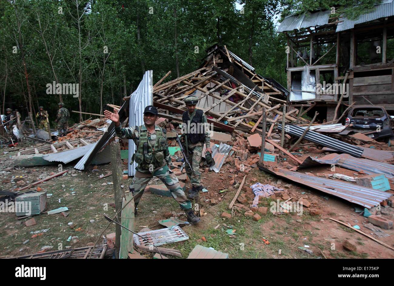 (140525)--SRINAGAR, 25. Mai 2014 (Xinhua)--eine indische Armee Offizier Gesten in der Nähe von einem zerstörten Haus nach einer Schießerei in das Dorf der Nowpora-Frisal in Kulgam Bezirk, etwa 55 km südlich von Srinagar, die Sommerhauptstadt von Indien kontrollierten Kaschmir, 25. Mai 2014. Zwei Militante Sonntag in einer wilden Schießerei mit indischen Truppen in Kaschmir Indien kontrollierten getötet wurden, teilte die Polizei mit. (Xinhua/Javed Dar) Stockfoto