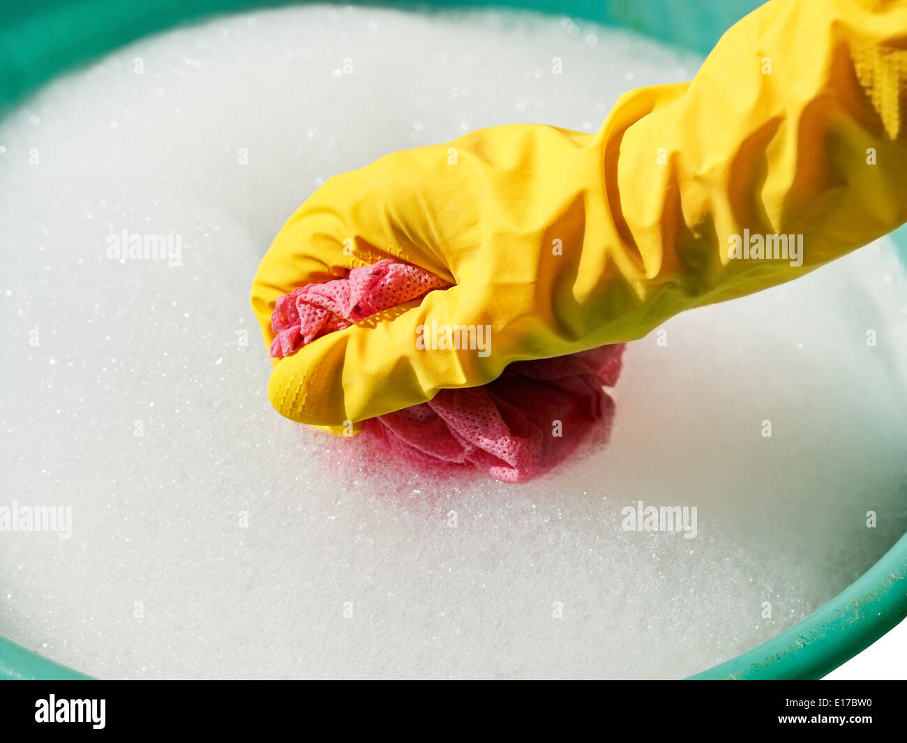 Hand im gelben Gummihandschuh nasses Tuch im schäumenden Wasser spülen Stockfoto