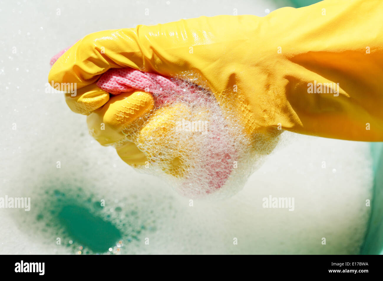 Hand im gelben Gummihandschuh ringt, nassen Duster von Seifenwasser Stockfoto