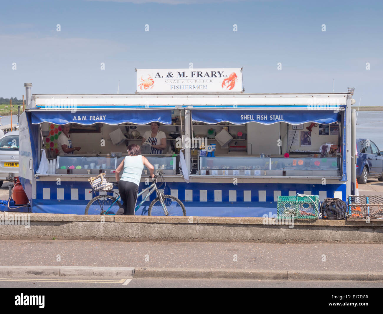 Frau mit dem Fahrrad von einer Shell Fisch stand auf Wells Hafen Norfolk zu kaufen Stockfoto