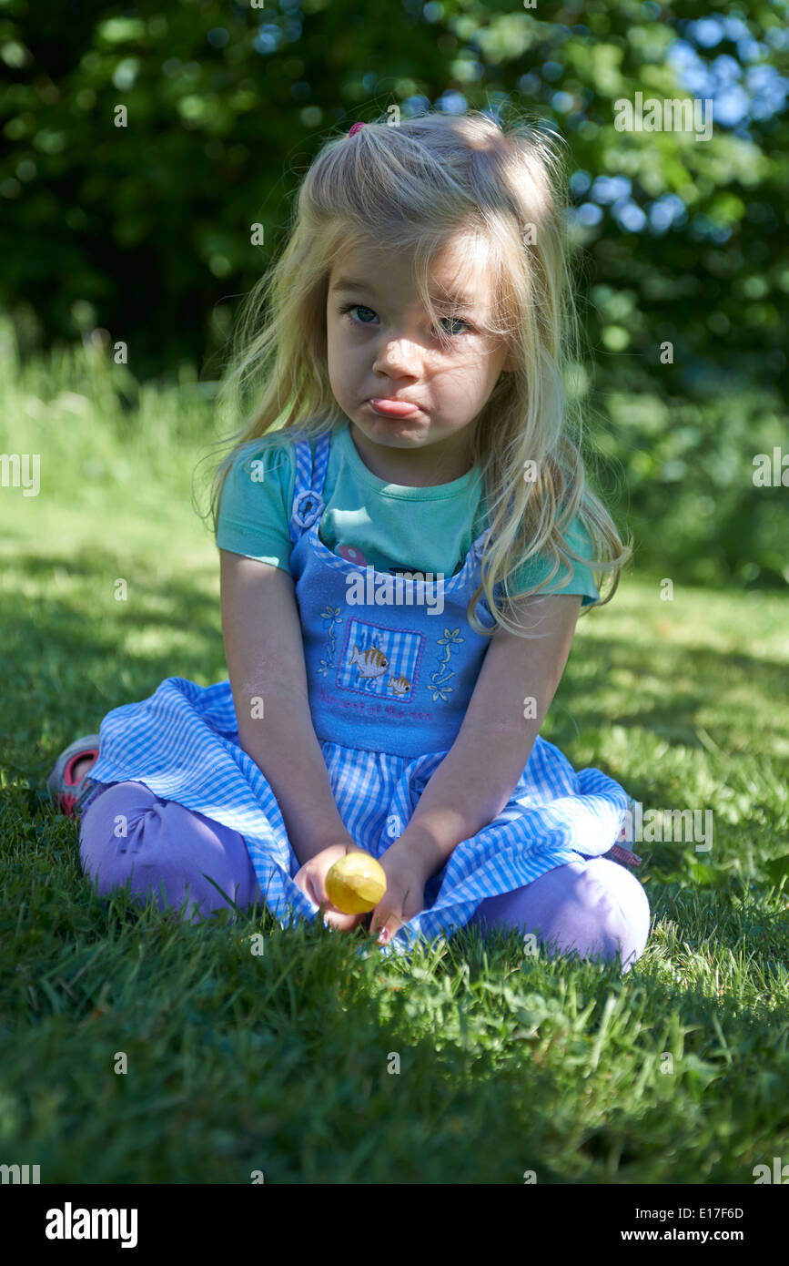 Kleine Kind blondes Mädchen lecken Lutscher draußen im Garten, portrait