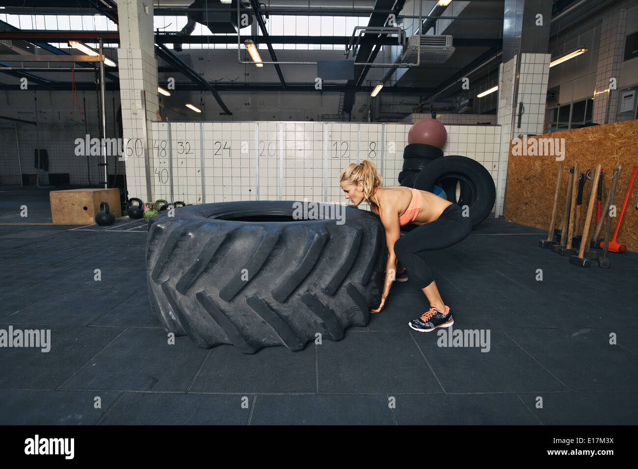 Harte Sportlerin spiegeln einen sehr großer Gummireifen. Junge Frau Crossfit Training im Fitness-Studio zu tun. Stockfoto