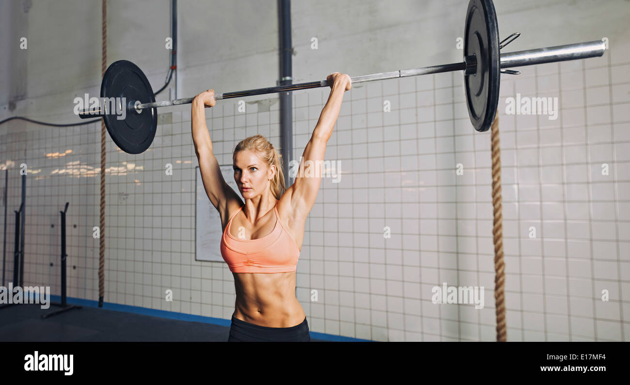 Muskulöse junge Frau Gewichtheben bei Crossfit Gym zu tun. Weibliches Model Heben schwerer Gewichte im Fitnessstudio fit. Stockfoto