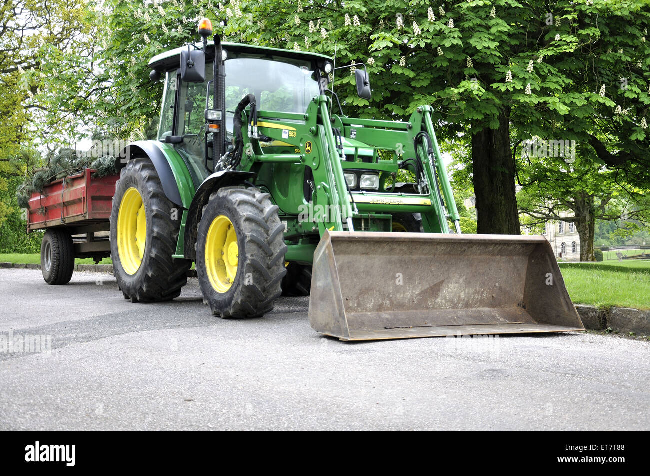 Green John Deere Traktor mit Schaufel am Vorder- und roten Anhänger geparkt  auf Weg Stockfotografie - Alamy