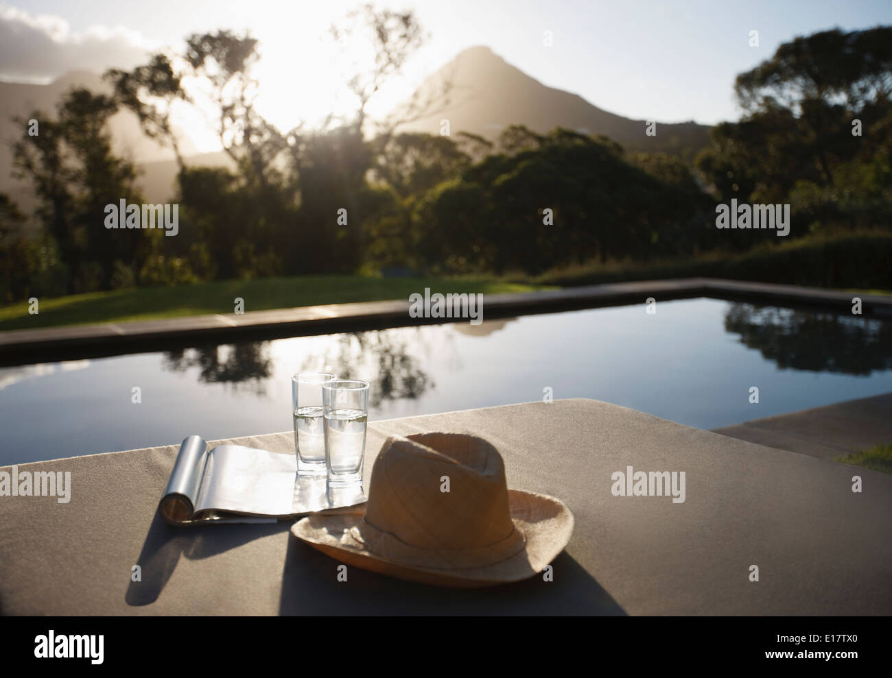 Sonnenhut, Wassergläser und Magazine auf den Liegestühlen am Pool Stockfoto