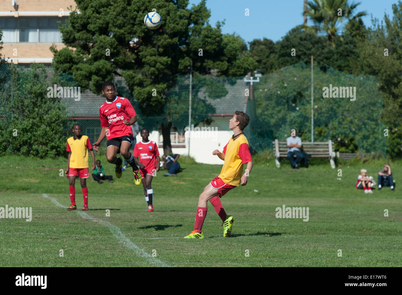 Junior-Football-Spieler springt in die Luft in Richtung den Ball, Cape Town, Südafrika Stockfoto