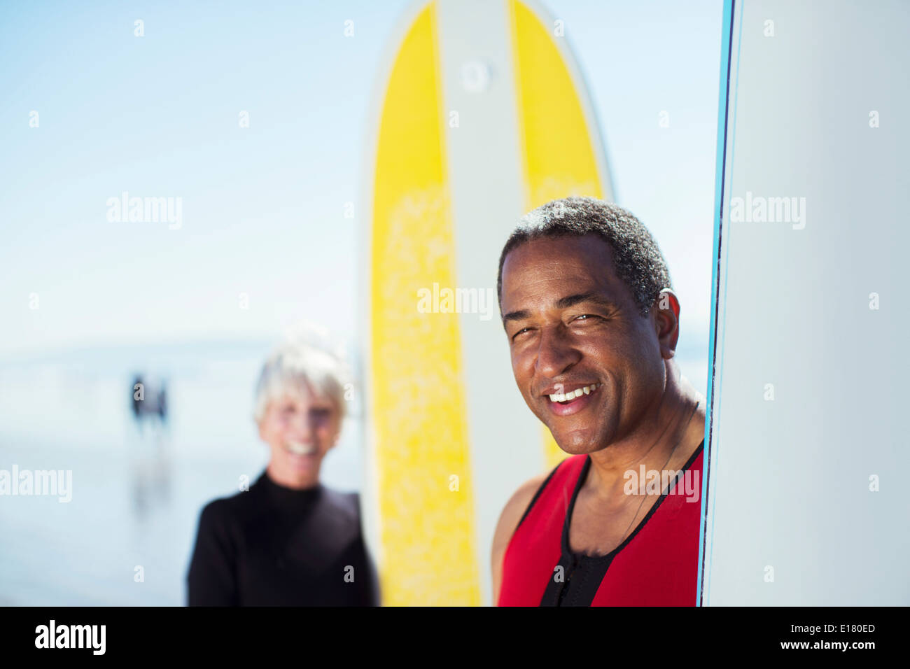 Porträt von älteres Paar mit Surfbrettern am Strand Stockfoto