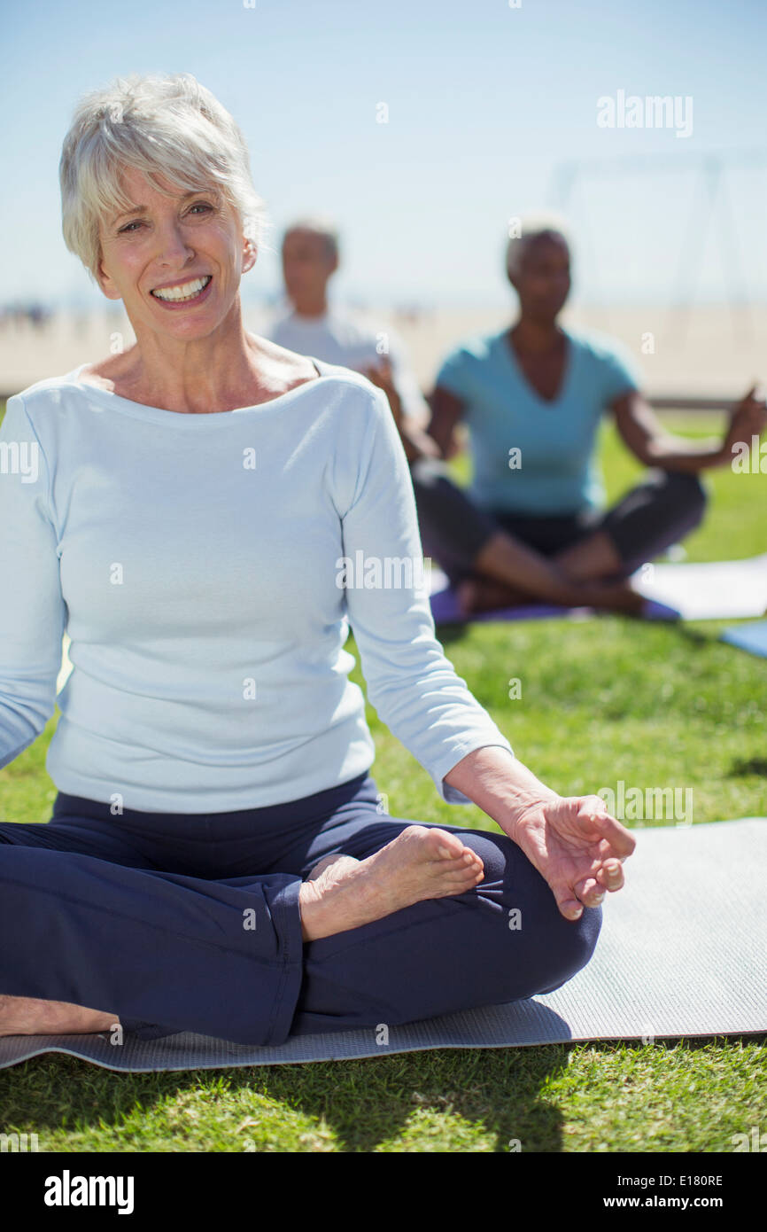 Porträt der lächelnde senior Frau praktizieren Yoga im park Stockfoto