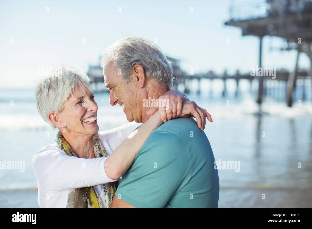 Älteres paar umarmt am Strand Stockfoto