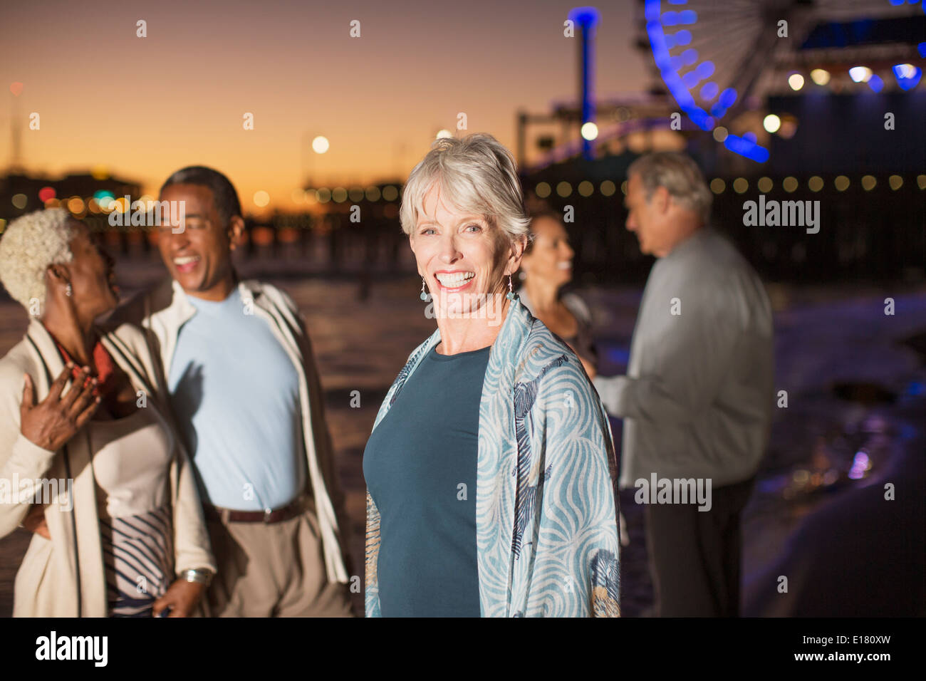 Porträt von enthusiastischen senior Frau mit Freunden am Strand in der Nacht Stockfoto