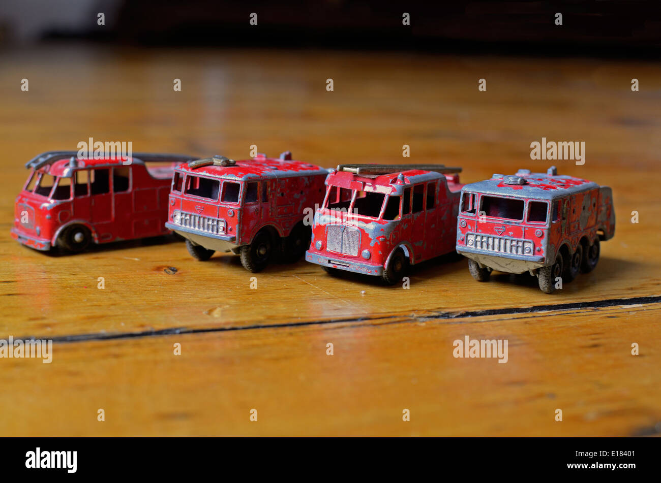Vier Matchbox Spielzeug Feuerwehrautos aufgereiht in einer Reihe auf einem Holzfußboden Stockfoto