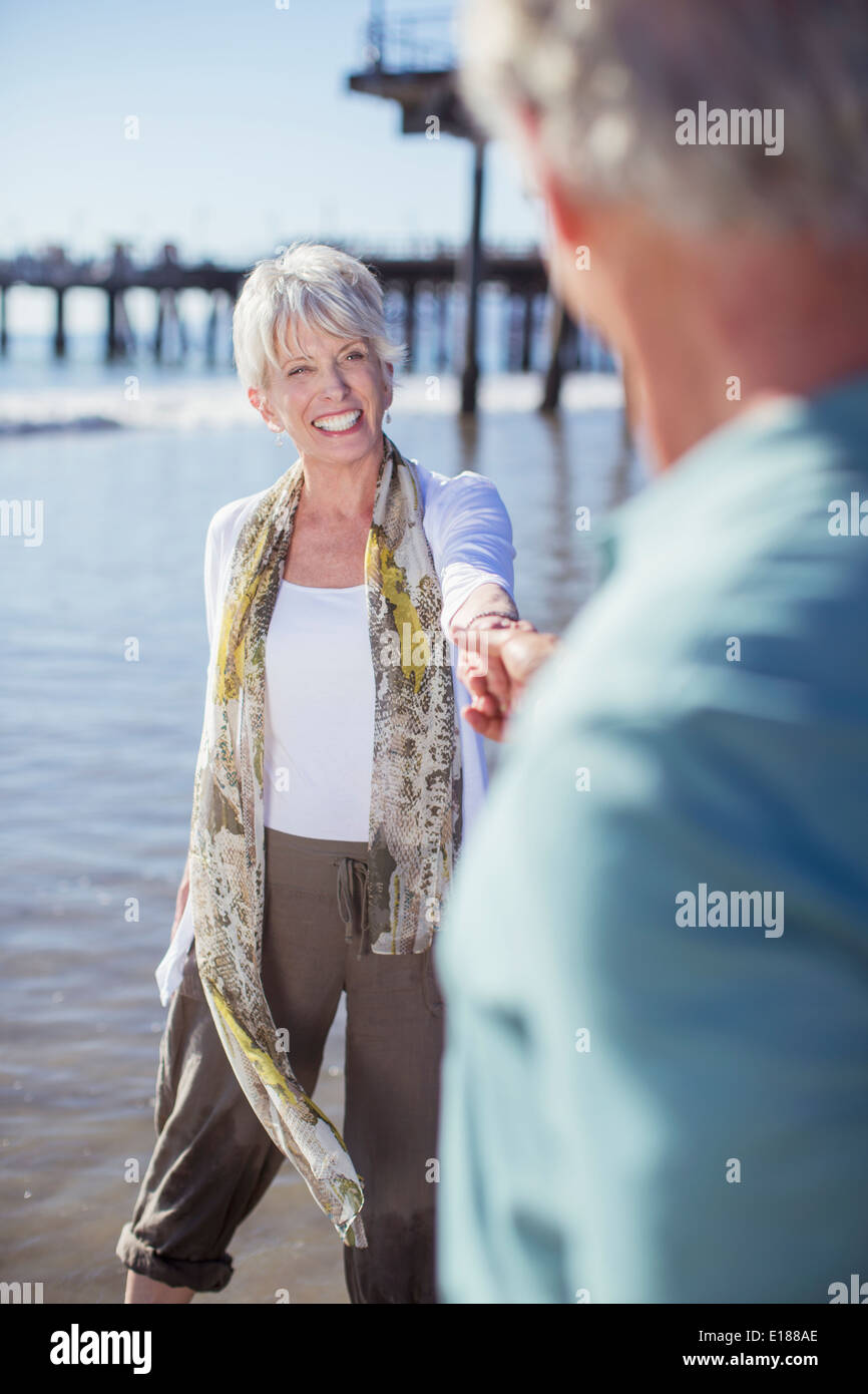 Älteres Paar halten die Hände am Strand Stockfoto
