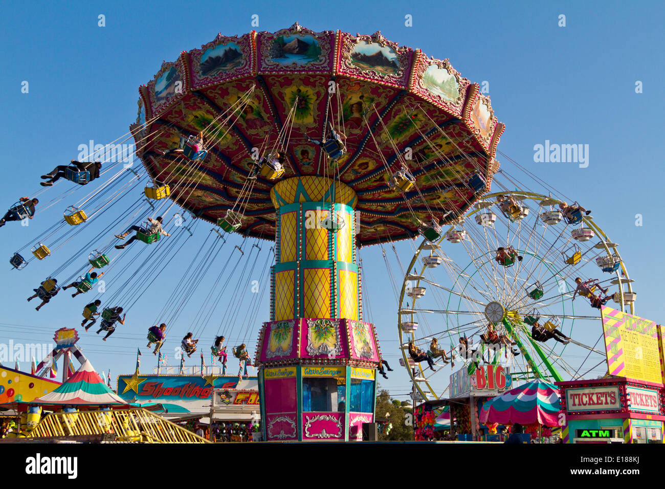 Personen, die Spinnen in der Luft hängend in Stühle auf einem Karneval fahren. Stockfoto