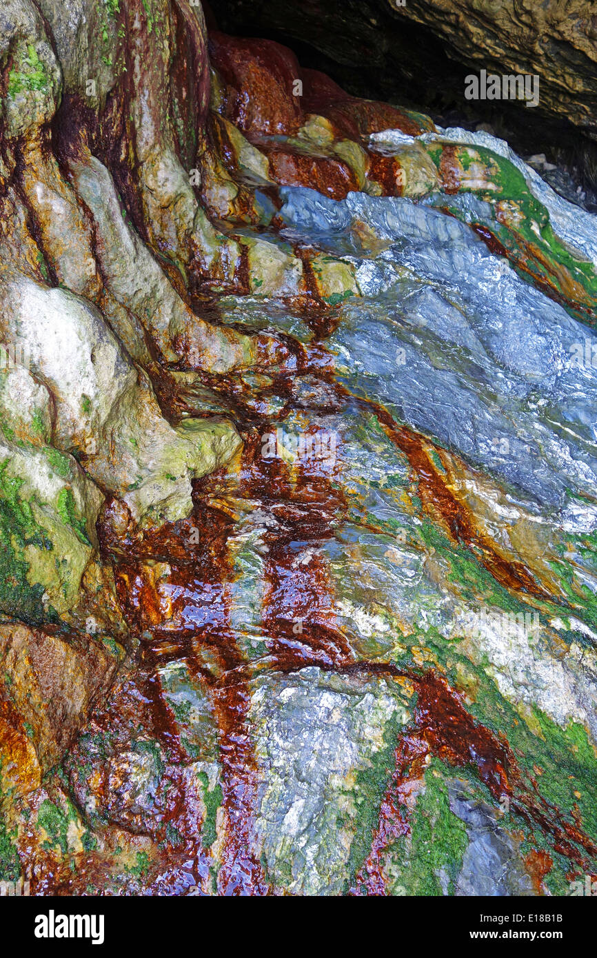 Felsen, die durch Regenwasser sickert durch mineralische Ablagerungen aus dem Zinn Bergbau in den Boden oben gefärbt Stockfoto