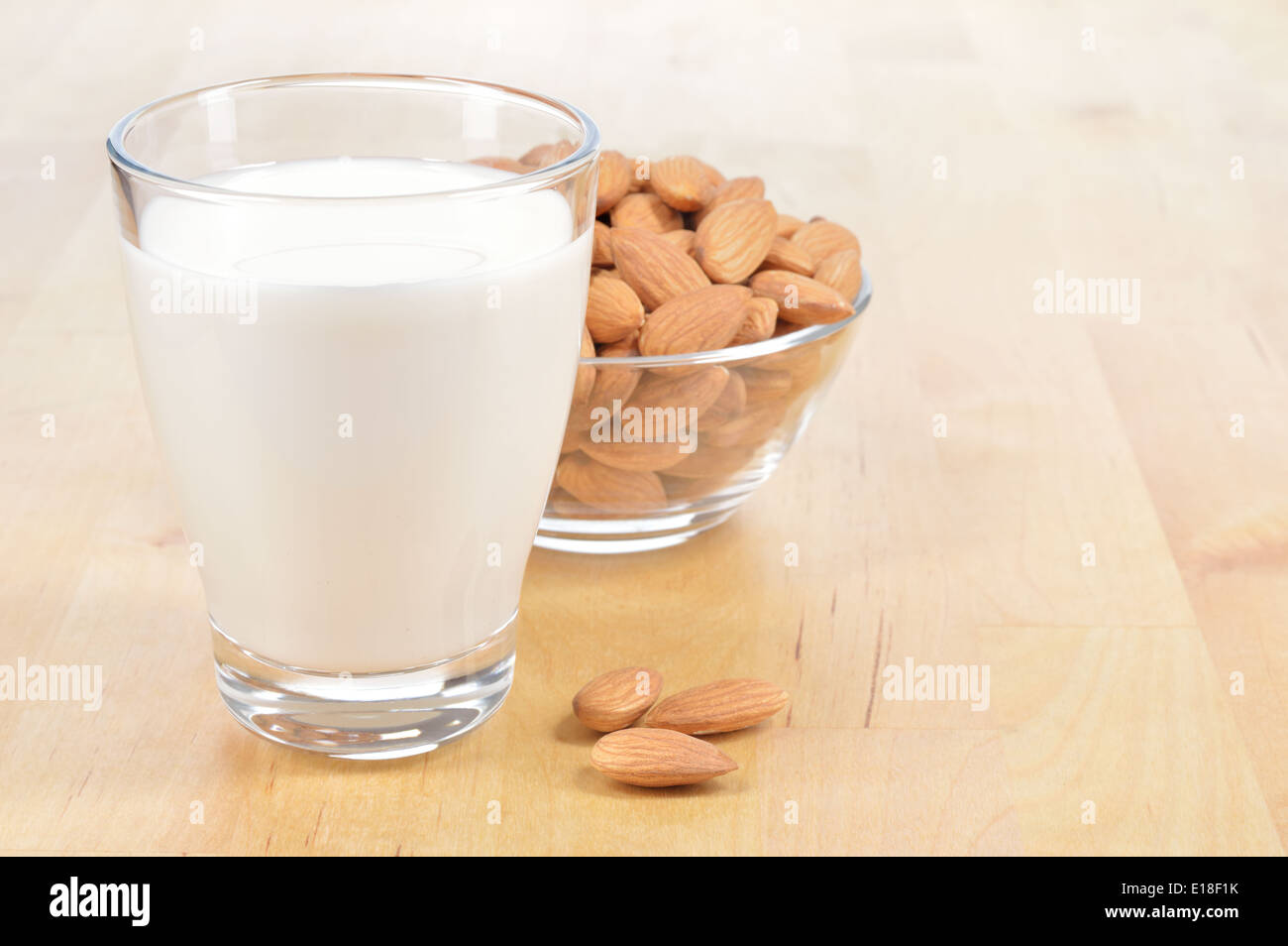 Mandel-Milch als Ersatz für Kuhmilch. Glas Mandelmilch und Schüssel mit Mandeln auf einem Holztisch. Stockfoto