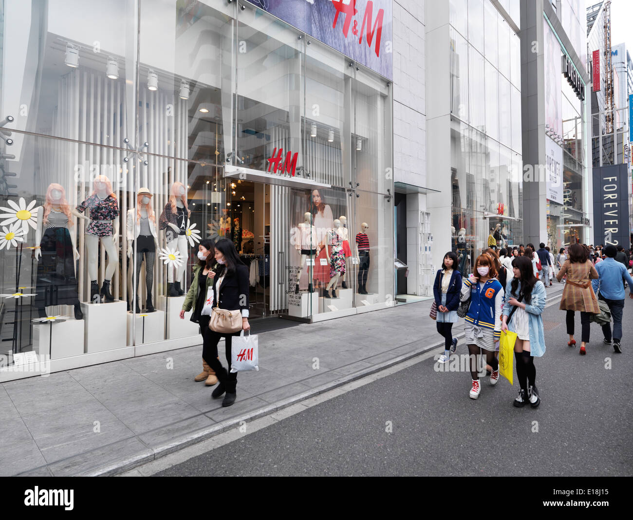 Junge Menschen gehen auf Straßen in Mode-Viertel Tokios. HM und Forever 21 Mode Bekleidungsgeschäfte in Tokio Stockfoto