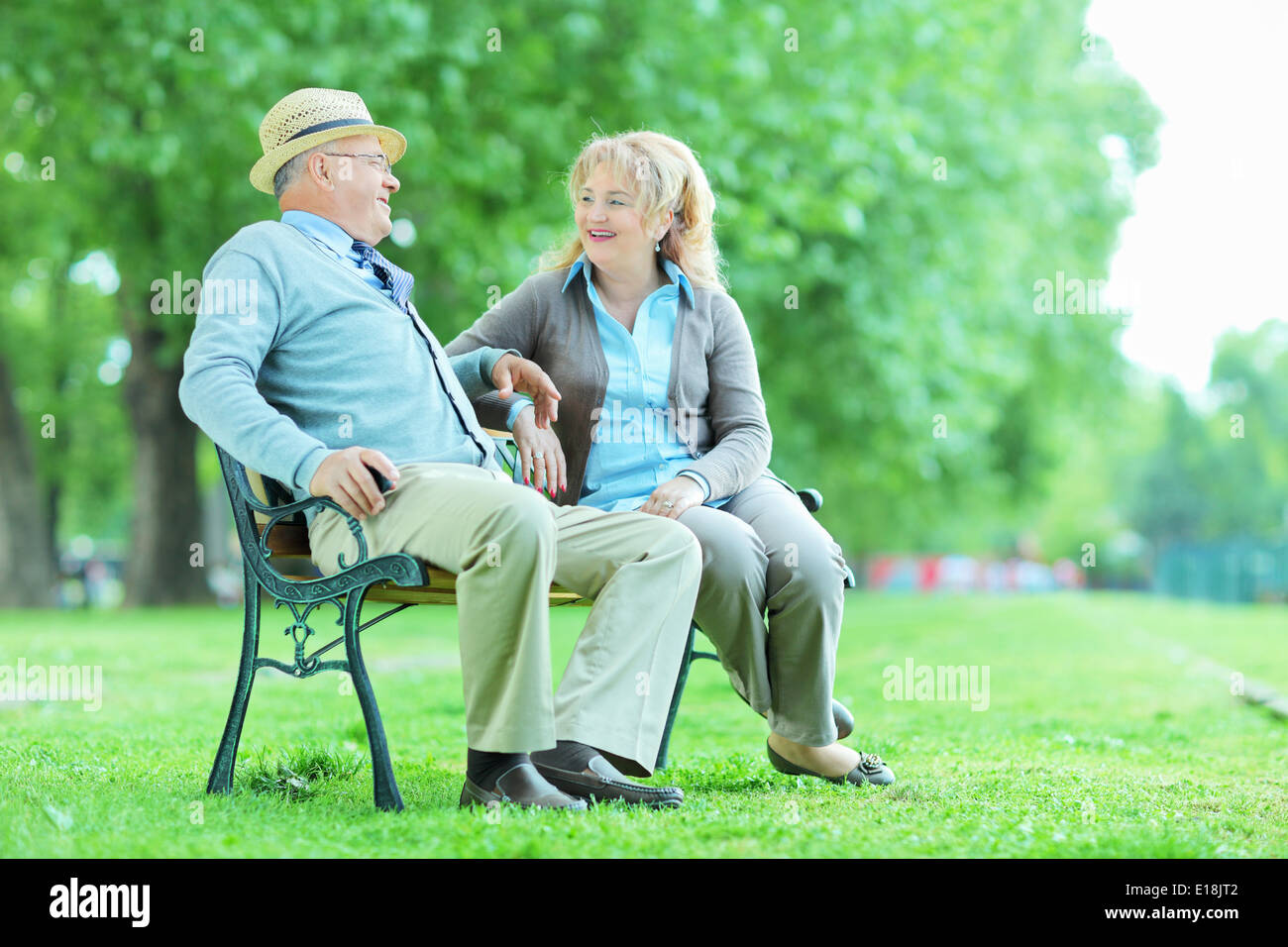 Entspannen Sie sich auf eine Bank im freien älteres Ehepaar Stockfoto
